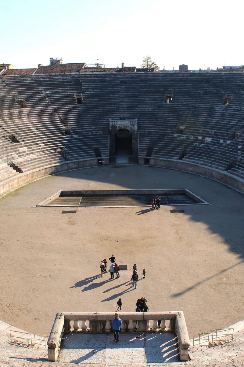 Die Arena di Verona — das elliptische römische Amphitheater an der Piazza Bra, dessen rosafarbene und weiße Kalksteinränge sich gegen einen klaren Veroneser Himmel erheben